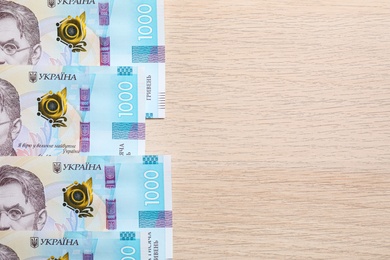 Ukrainian money on wooden background, flat lay. Space for text