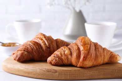 Photo of Fresh croissants on white wooden table. Tasty breakfast