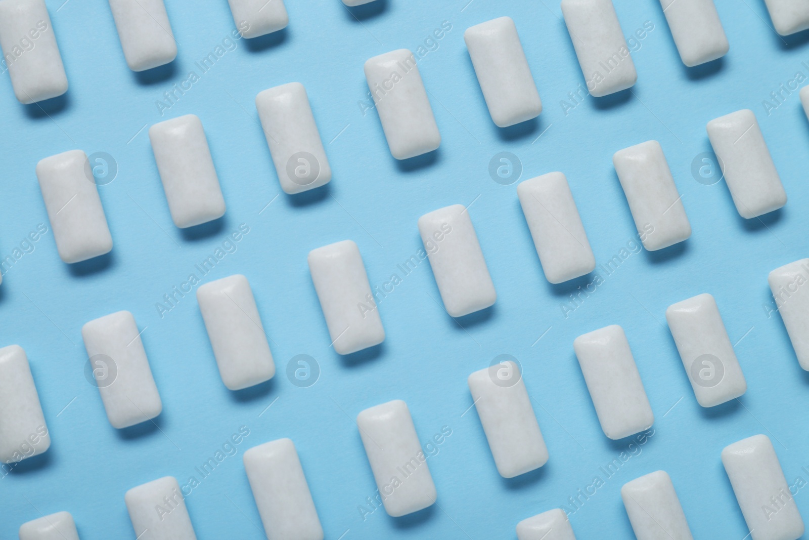 Photo of Tasty white chewing gums on light blue background, flat lay