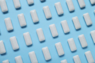 Tasty white chewing gums on light blue background, flat lay