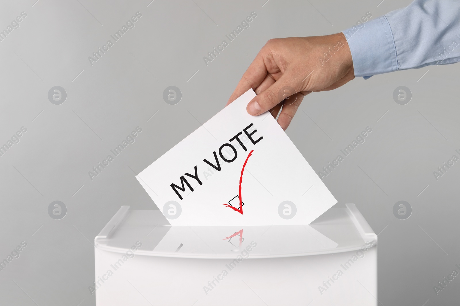 Image of Man putting paper with text My Vote and tick into ballot box on light grey background