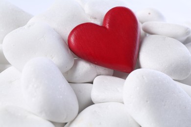 Photo of Decorative heart on white pebble stones, closeup