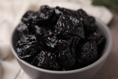 Sweet dried prunes in bowl on table, closeup