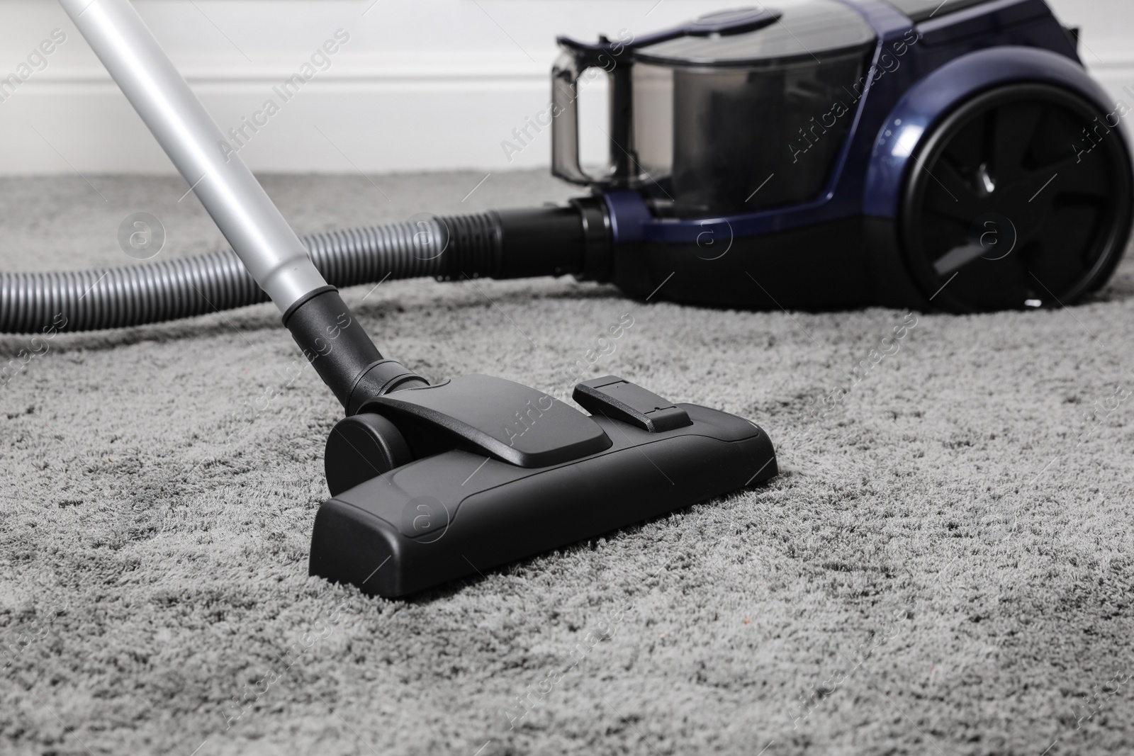 Photo of Modern black vacuum cleaner on carpet indoors