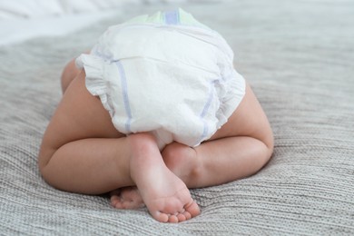 Cute little baby in diaper on bed