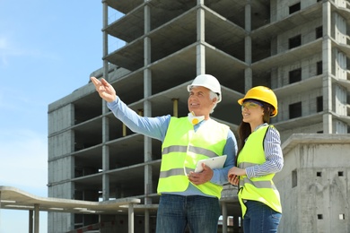 Photo of Professional engineer and foreman with tablet in safety equipment at construction site