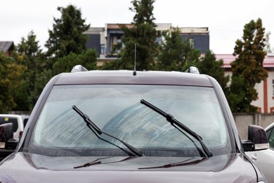 Photo of Car wipers cleaning water drops from windshield glass outdoors