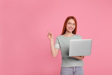 Photo of Smiling young woman with laptop on pink background, space for text