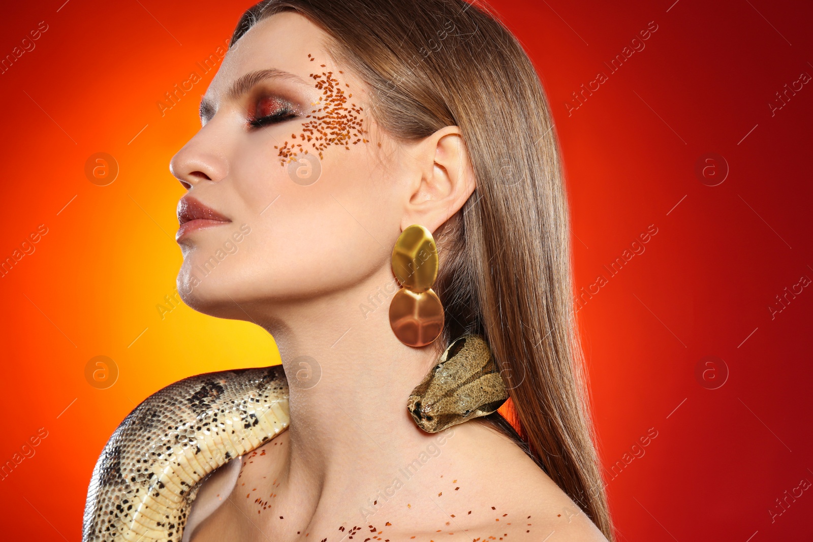 Photo of Beautiful woman with boa constrictor on bright colorful background, closeup