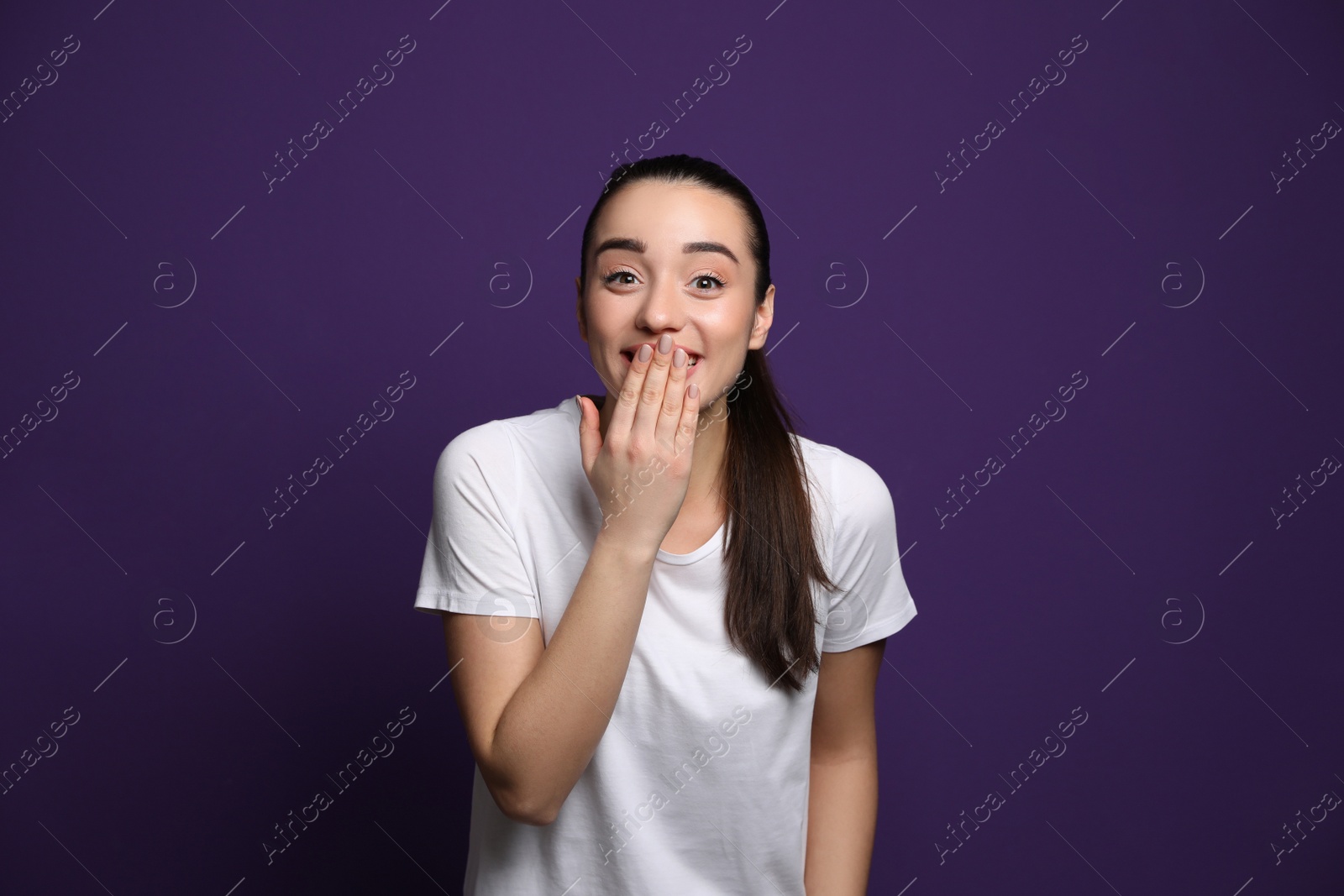 Photo of Beautiful young woman laughing on purple background. Funny joke