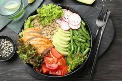 Healthy meal. Tasty products in bowl and cutlery on black wooden table, flat lay