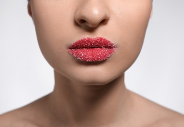 Photo of Young woman with lips covered in sugar on light background, closeup
