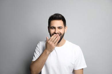Young man laughing on light grey background. Funny joke