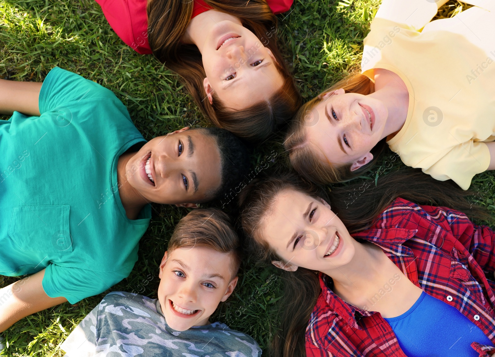 Photo of Group of children lying on grass, top view. Summer camp