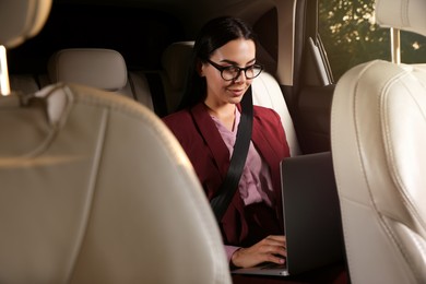 Young woman working on laptop in modern taxi