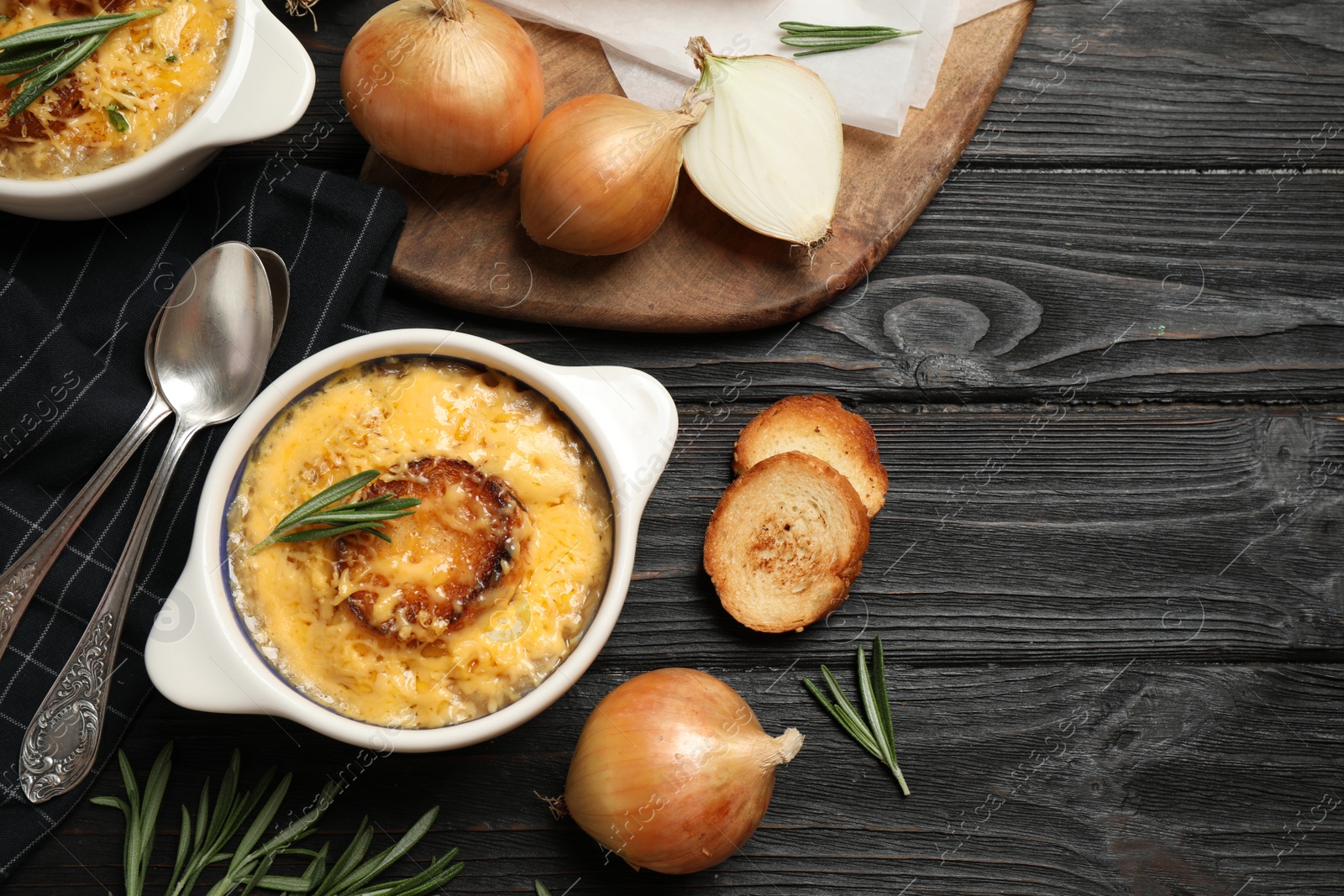 Photo of Tasty homemade french onion soup served on black wooden table, flat lay