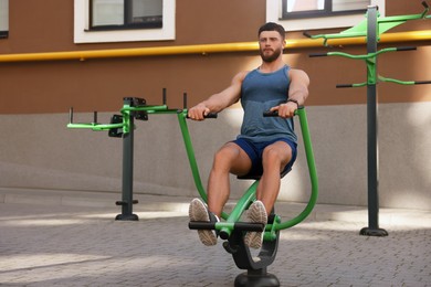 Photo of Man training on rowing machine at outdoor gym