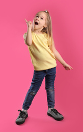 Photo of Full length portrait of emotional little girl on pink background