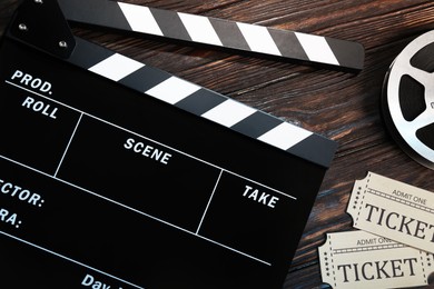 Photo of Clapperboard, movie tickets and film reel on wooden table, flat lay