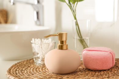 Photo of Dispenser, cotton swabs and sponge on countertop in bathroom