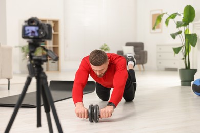 Trainer with ab wheel recording workout on camera at home