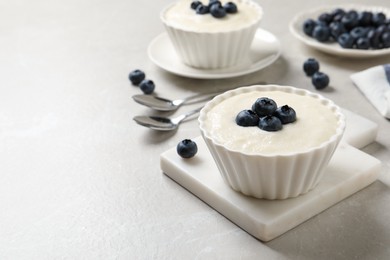 Photo of Delicious semolina pudding with blueberries on white table, space for text