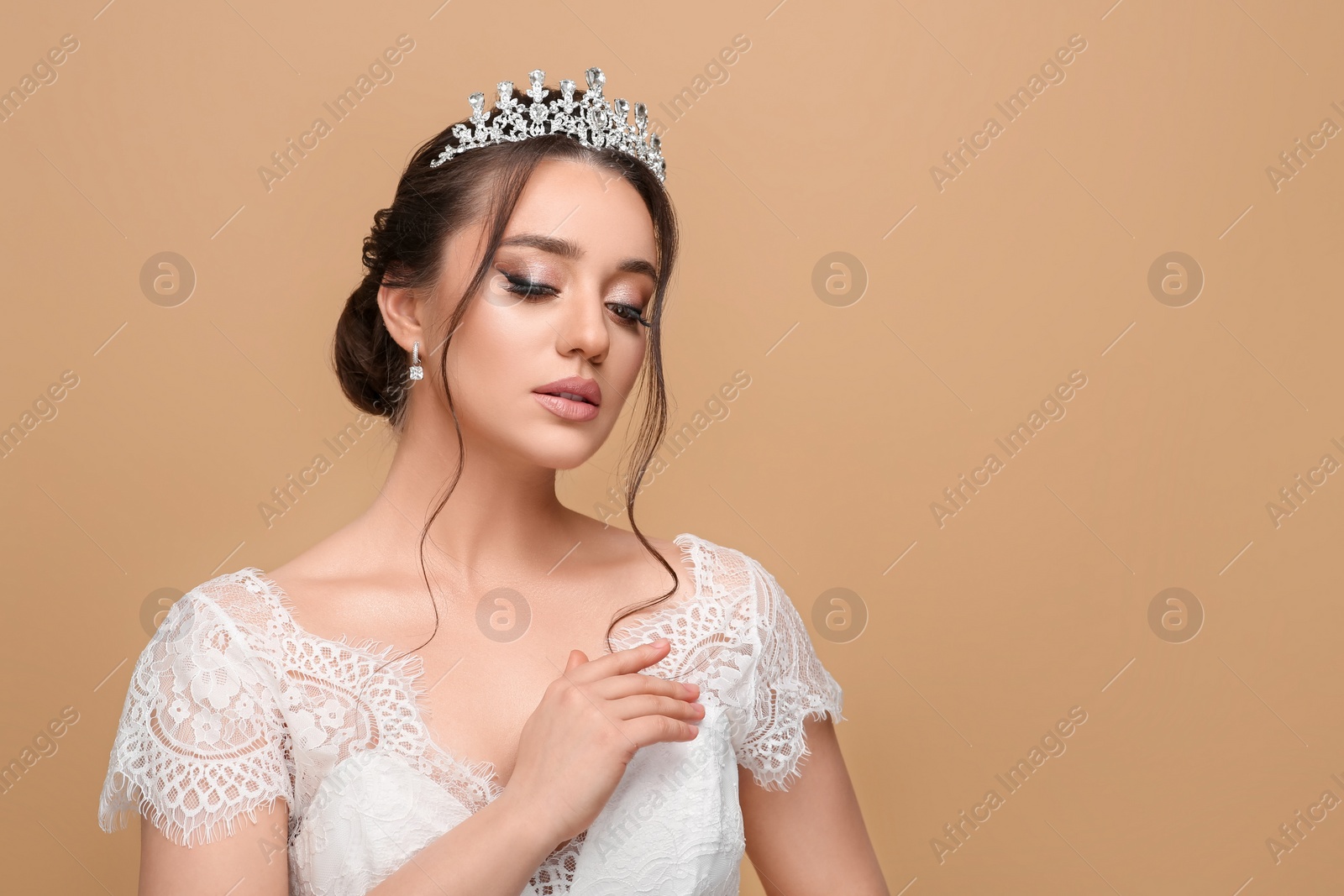 Photo of Beautiful young woman wearing luxurious tiara on beige background, space for text