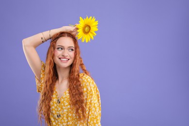 Photo of Beautiful young hippie woman with sunflower on violet background, space for text