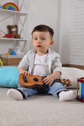 Cute little boy with toy guitar at home