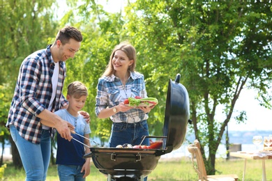 Photo of Happy family having barbecue with modern grill outdoors