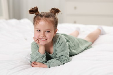 Portrait of happy little girl on bed at home