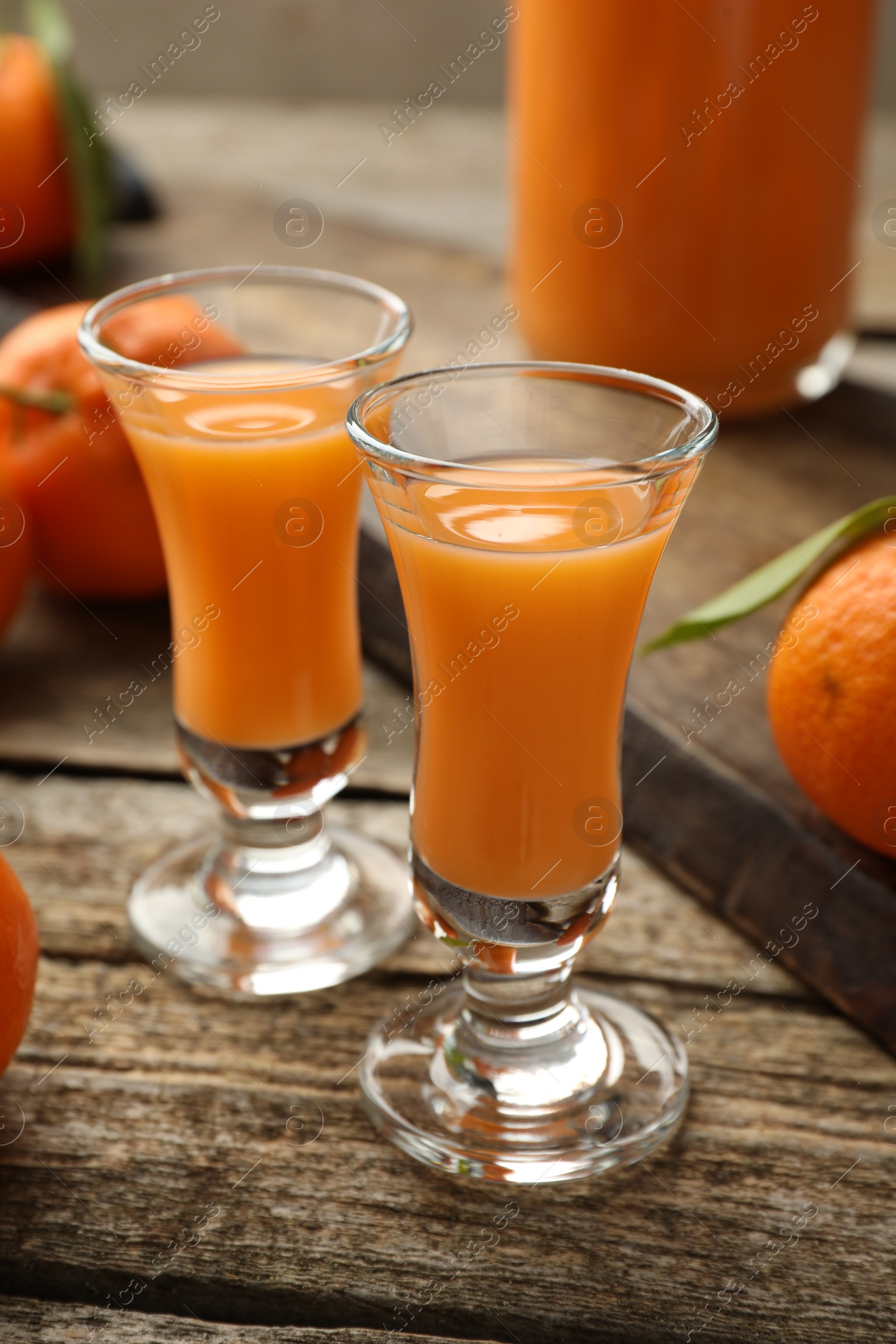 Photo of Delicious tangerine liqueur and fresh fruits on wooden table