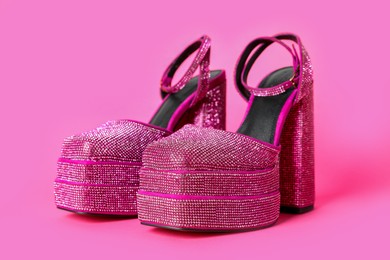 Photo of Fashionable punk square toe ankle strap pumps on pink background. Shiny party platform high heeled shoes