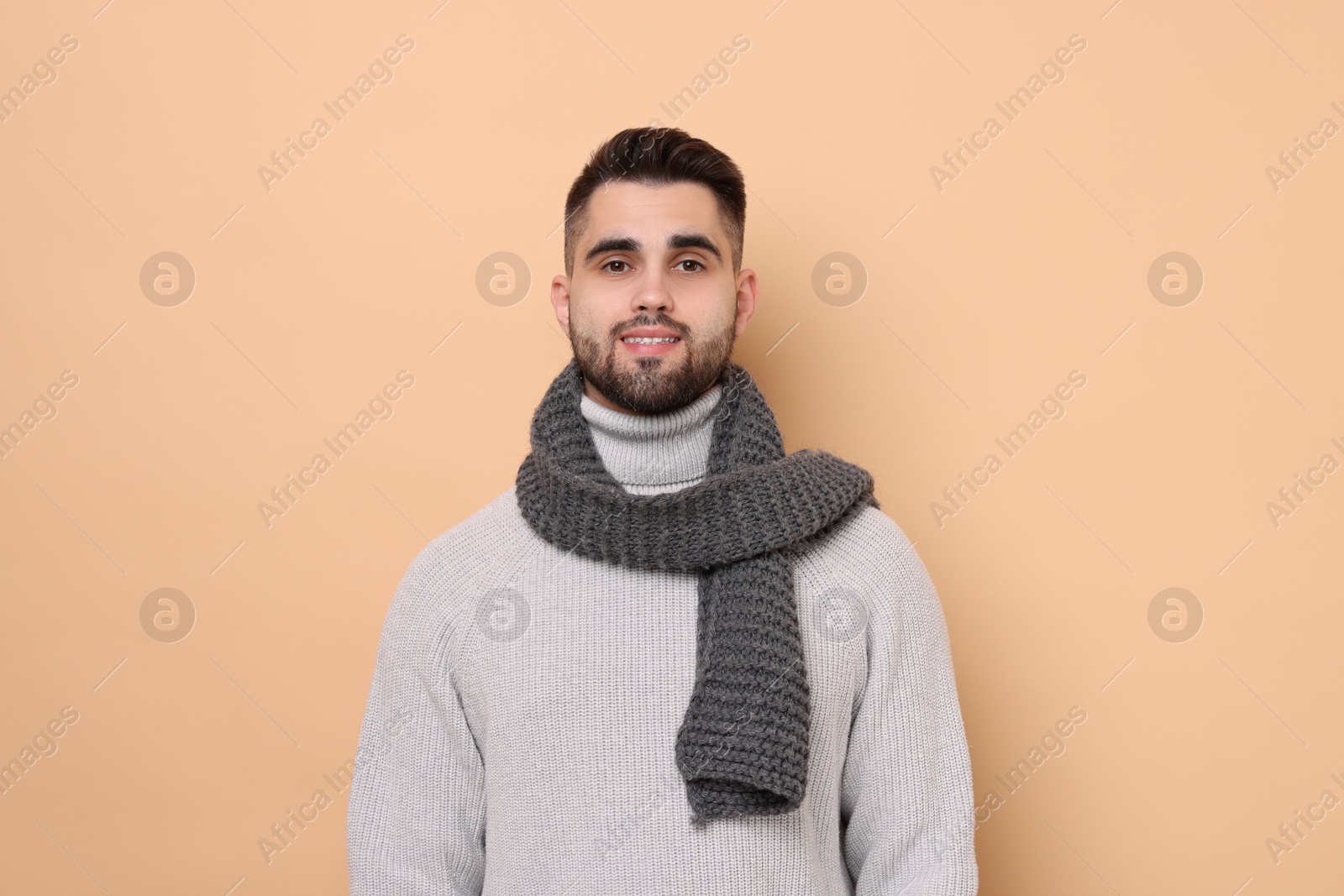 Photo of Smiling man in knitted scarf on beige background