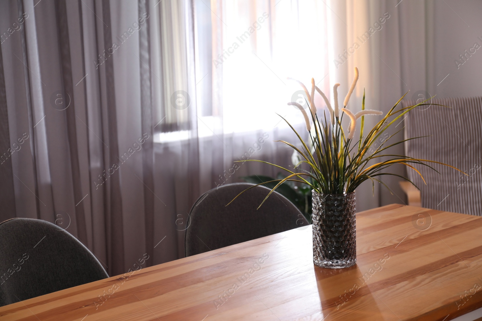 Photo of Vase on wooden table near window with curtains in room