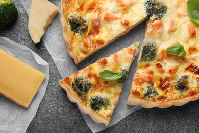 Delicious homemade quiche and ingredients on gray table, flat lay