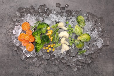 Different frozen vegetables with ice on grey textured table, top view