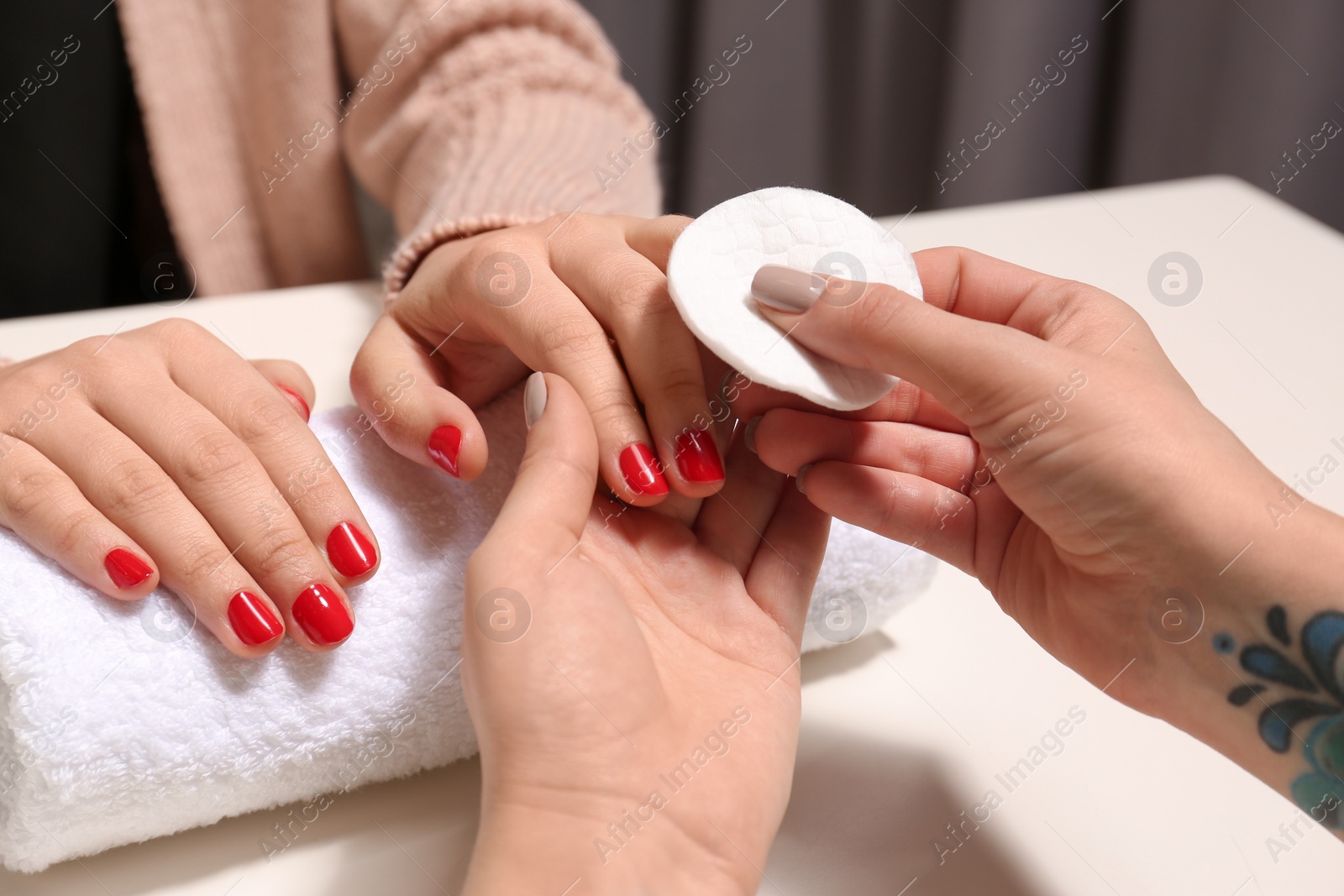 Photo of Manicurist removing polish from client's nails in salon, closeup