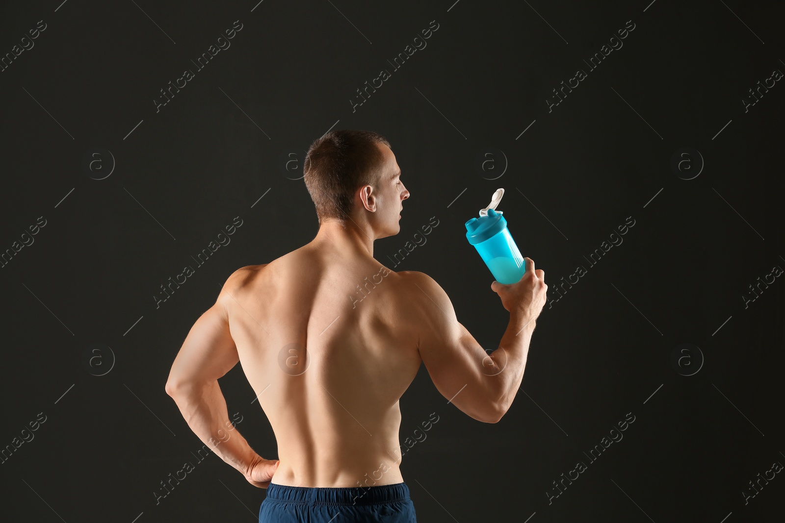 Photo of Athletic young man with protein shake on black background