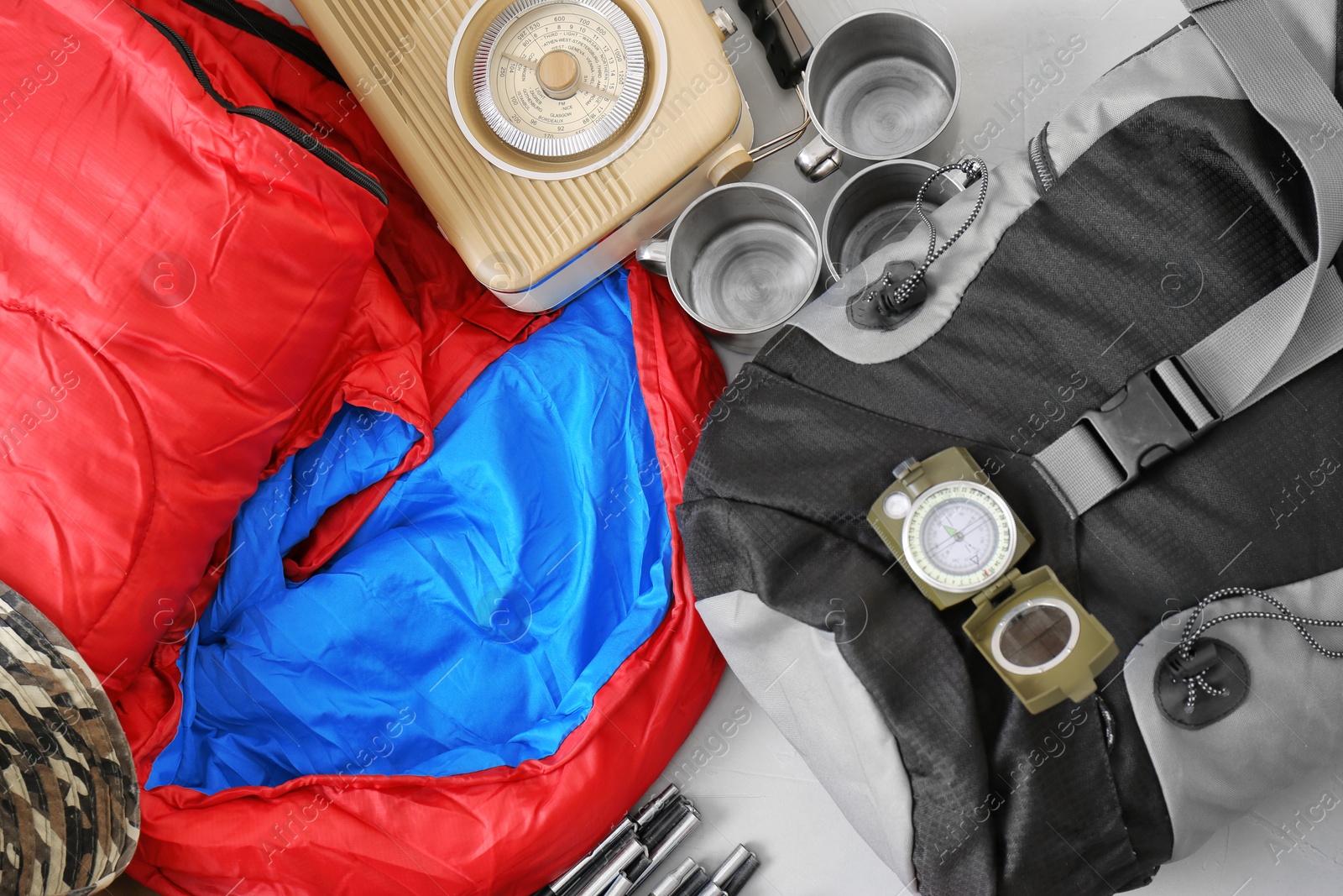 Photo of Flat lay composition with sleeping bag and camping equipment on grey background