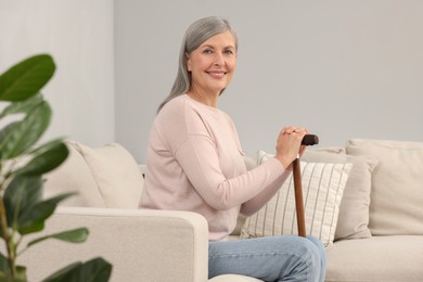 Photo of Mature woman with walking cane on sofa indoors