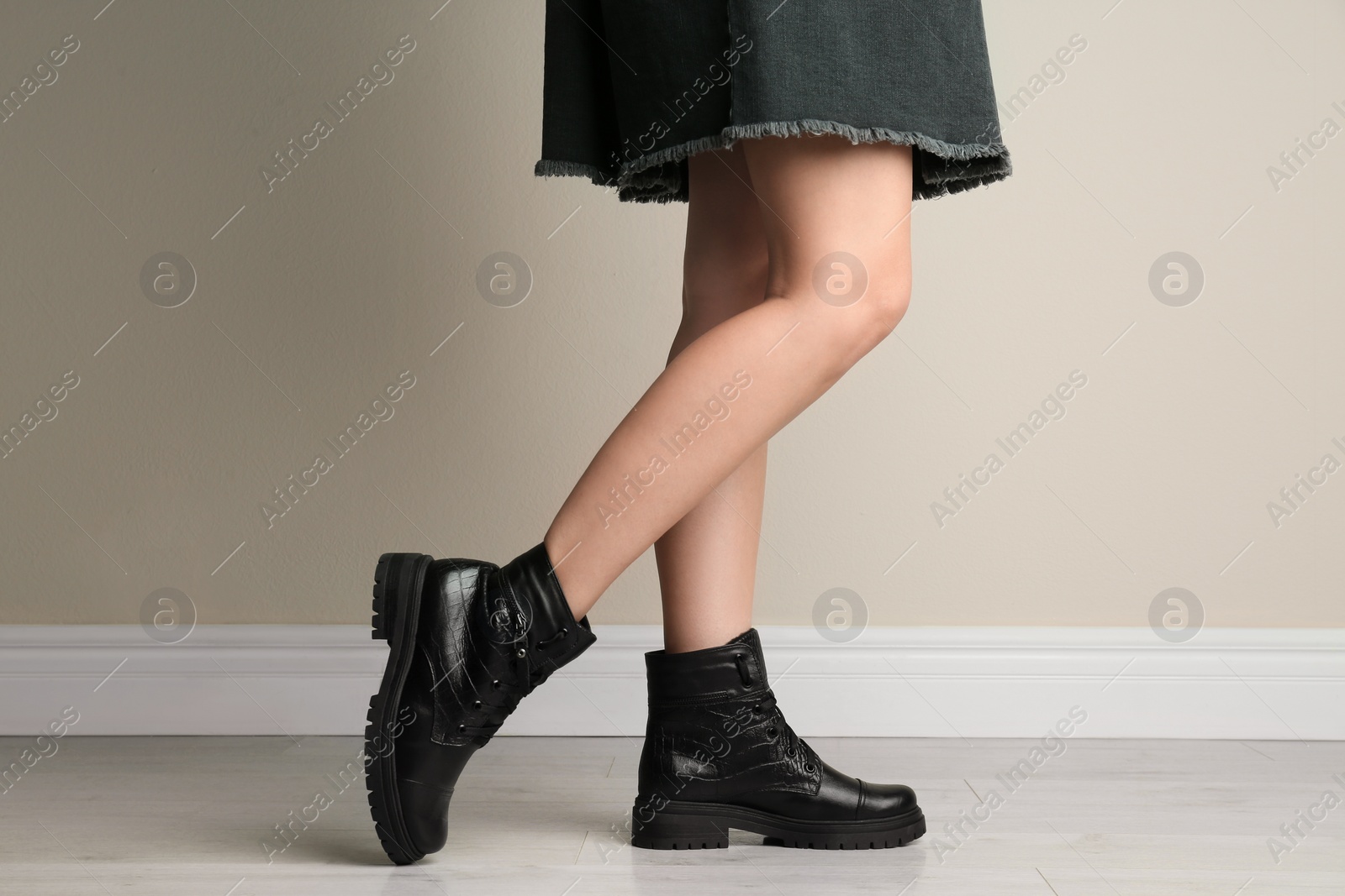 Photo of Woman wearing stylish boots near beige wall indoors, closeup