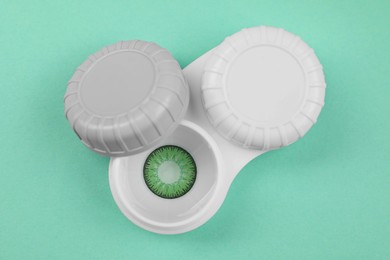 Photo of Case with green contact lenses on turquoise background, top view