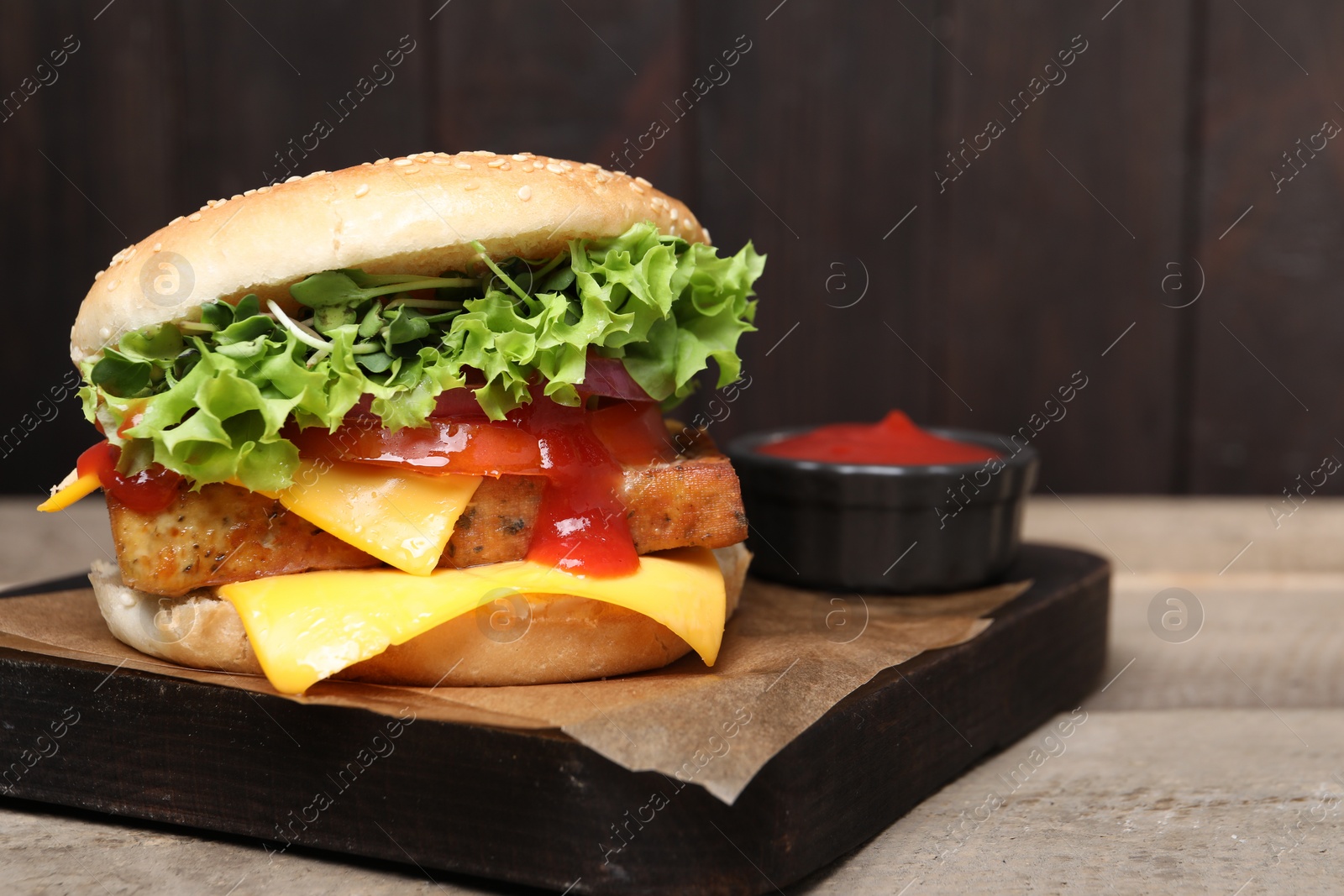 Photo of Delicious tofu burger served with sauce on wooden table, closeup. Space for text