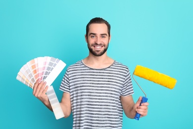 Photo of Young man with palette and roller on color background