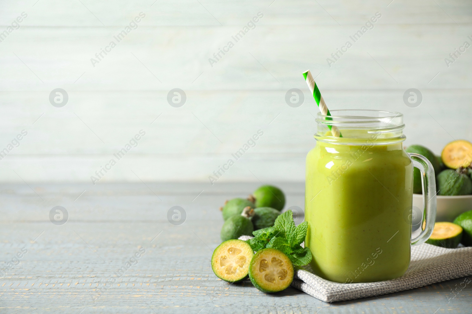 Photo of Fresh feijoa smoothie in mason jar on grey table, space for text