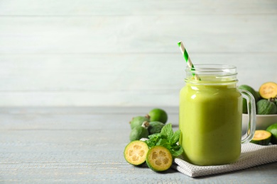 Fresh feijoa smoothie in mason jar on grey table, space for text