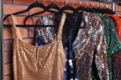 Rack with collection of fashionable dresses near brick wall in showroom. Preparing for party