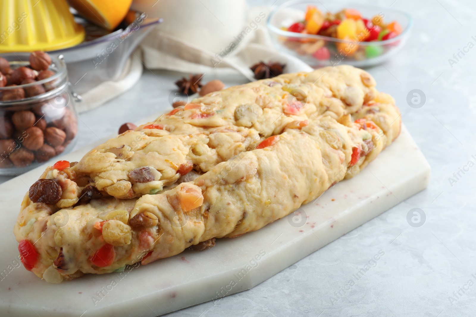 Photo of Unbaked Stollen with candied fruits and raisins on light marble table, closeup