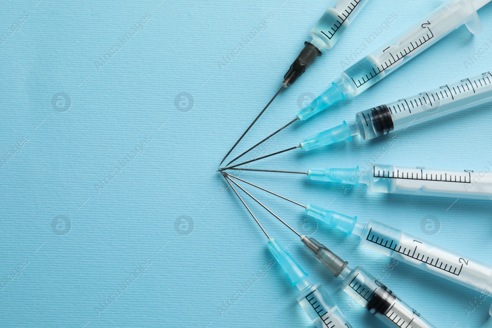 Photo of Disposable syringes with needles and medicine on light blue background, flat lay. Space for text